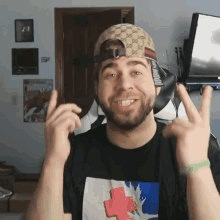 a man with a beard wearing a gucci hat and a black shirt with a cross on it
