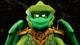 a green lego character with a mask and a shield on his chest