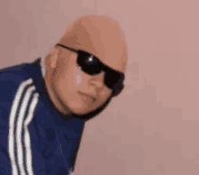 a bald man wearing sunglasses and a fake head is looking at the camera .