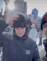 a man wearing a black beanie with a red t on it