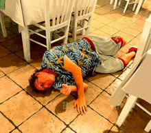 a man in a hawaiian shirt is laying on the floor holding a shot glass