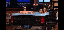 a man and a woman are sitting in a truck bathtub with a license plate that says shrktnk