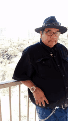 a man wearing a hat and glasses is standing on a balcony