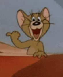 jerry from tom and jerry is waving his hand and smiling .