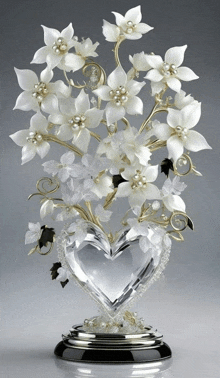 a heart shaped vase with white flowers and pearls on it