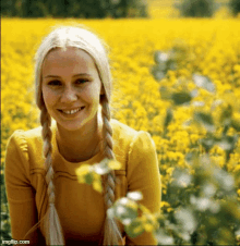 a woman in a yellow dress is smiling in a field of yellow flowers ..