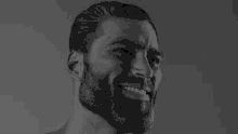 a black and white photo of a man with a beard smiling and looking at the camera .