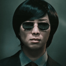 a man wearing sunglasses and a suit has a serious look on his face