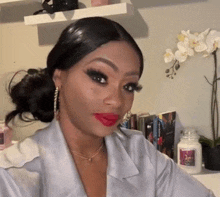 a woman wearing red lipstick and earrings is taking a selfie in a room .