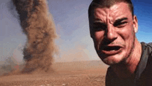 a man is making a funny face in front of a sandstorm .