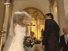 a bride and groom are standing in front of a crucifix in a church with a tvf logo in the background