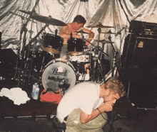 a man kneeling in front of a drum set that says pearl