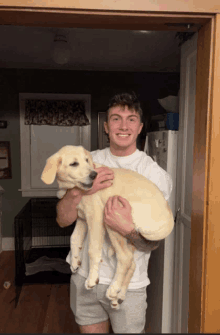 a man in a white shirt is holding a yellow dog in his arms