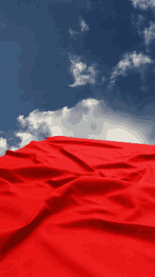 a red cloth is against a blue sky with clouds