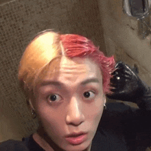 a young man with red hair is taking a selfie in the bathroom .