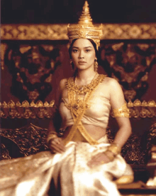 a woman in a white and gold costume is sitting on a chair