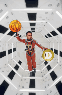 a man in a space suit is holding two gold coins with the letter m and d on them