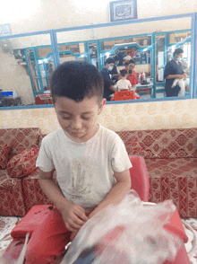 a boy in a white shirt with the number 10 on it sits on a red couch