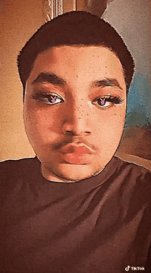 a man with fake eyelashes and freckles looks at the camera with a tiktok watermark on the bottom