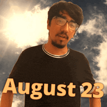 a man wearing glasses and a black shirt that says august 23 on it