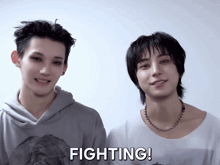 two young men are standing next to each other and the word fighting is on the bottom right