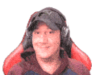 a man wearing a hat and headphones is smiling while sitting in a red chair .