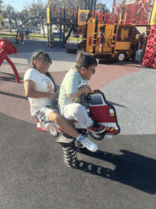 a boy and a girl are riding a fire truck rocking horse