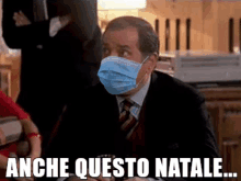 a man in a suit and tie wearing a face mask with the words anche questo natale below him