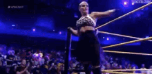 a woman in a skirt is standing in a wrestling ring with her arms outstretched .