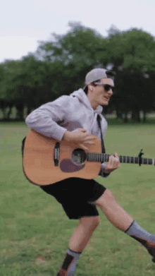 a man playing a guitar in a grassy field