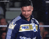 a wrestler wearing a blue and gold jacket with the word page on it