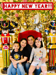 a family posing for a picture in front of a christmas tree with a happy new year sign behind them