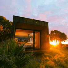 the sun is setting behind a small house