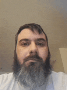 a man with a beard is taking a selfie with his phone .