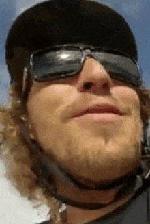 a man wearing sunglasses and a helmet is smiling