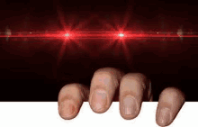 a close up of a person 's hand reaching out from behind a wall with red lights behind them .