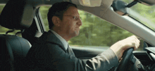 a man wearing glasses is driving a car and making a funny face
