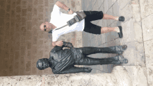 a man stands next to a statue of a man talking on a cell phone