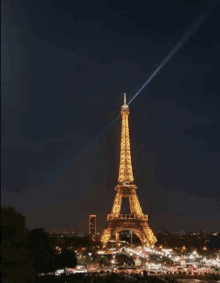 the eiffel tower is lit up at night with a blue light coming from the top