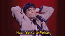 a man stands in front of a microphone with the words haan ye karlo pehle written below him