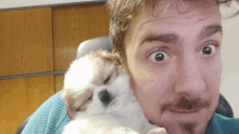 a man with a beard is holding a puppy in his arms