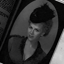 a black and white photo of a woman wearing a hat and earrings
