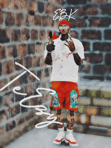 a man in a white shirt and red shorts is standing in front of a brick wall with the name ebk written on it