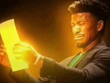 a man in a suit is holding a piece of paper that is lit up