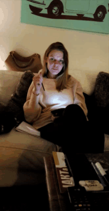 a woman is sitting on a couch with a cigarette in her hand and a box of cigarettes on the table