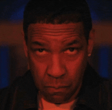 a close up of a man 's face with a red light behind him