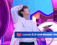a man is holding a cell phone in front of a sign that says lazada 11.11 our biggest online and watch your discounts