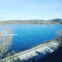 a blue lake with mountains in the background and a tiktok icon in the corner