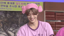 a young man wearing a pink and purple shirt and a pink headband is smiling .