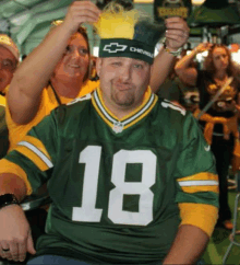 a man wearing a green bay packers jersey and a chevrolet hat